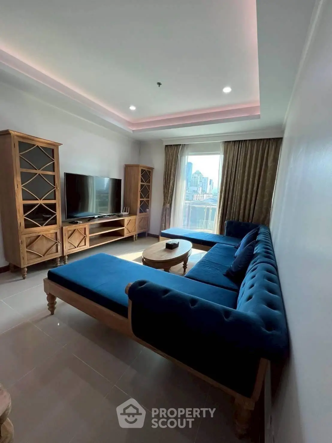 Spacious living room with elegant blue sofa and city view, perfect for relaxation and entertainment.