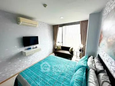 Modern bedroom with teal bedding, wall-mounted TV, and cozy seating area.