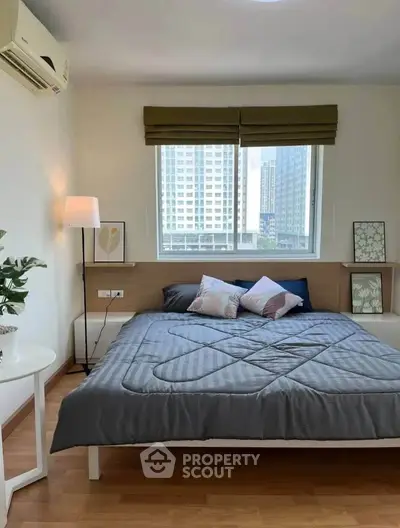 Modern bedroom with large window and city view, featuring stylish decor and cozy ambiance.