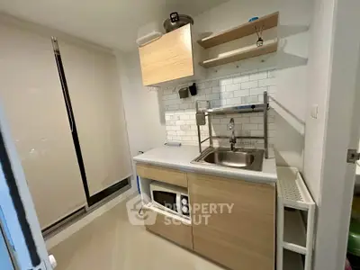 Modern compact kitchen with sleek cabinetry and built-in microwave