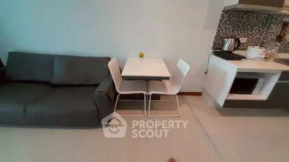 Modern living room with sleek sofa and compact dining area in stylish apartment.