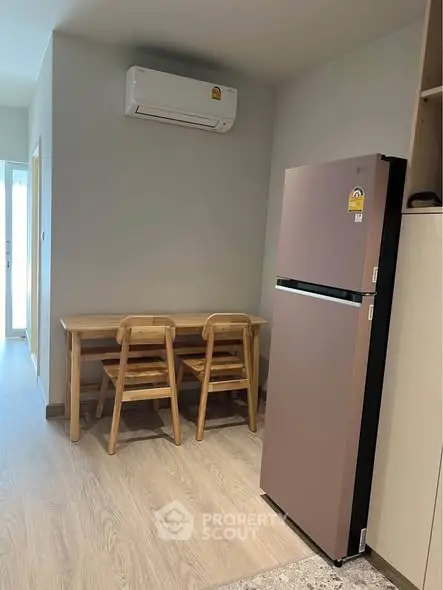 Cozy dining area with modern fridge and air conditioning in compact apartment.
