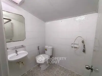 Spacious bathroom with modern fixtures and tiled walls, featuring a sleek sink and toilet.