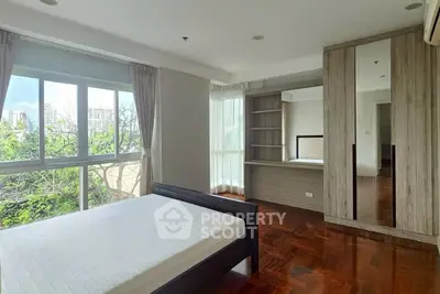Spacious bedroom with large windows and built-in wardrobe in modern apartment.