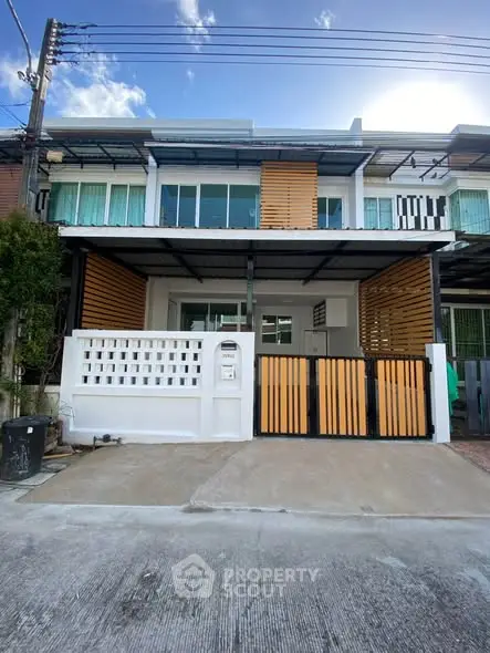 Modern townhouse exterior with stylish wooden accents and spacious driveway.