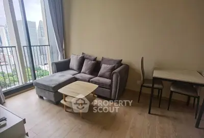 Modern living room with cozy gray sofa and city view balcony in high-rise apartment.