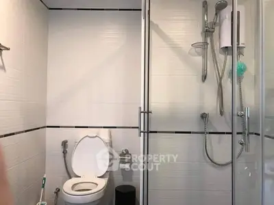 Modern bathroom with glass shower enclosure, sleek fixtures, and pristine white tiles offering a clean and minimalist aesthetic.