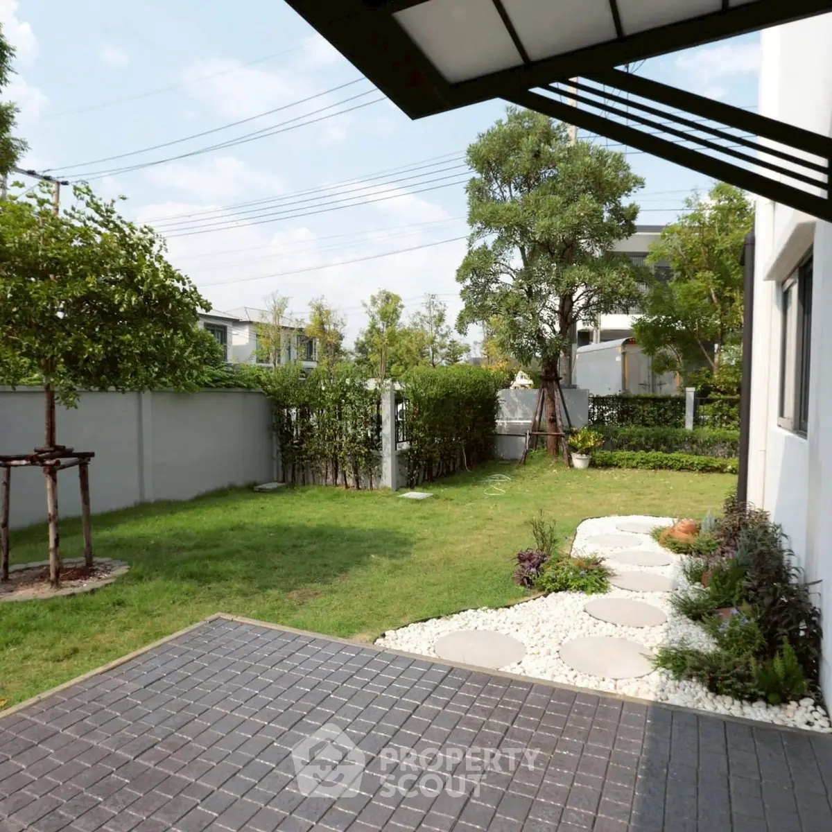 Charming backyard garden with lush greenery and modern patio, perfect for outdoor relaxation.