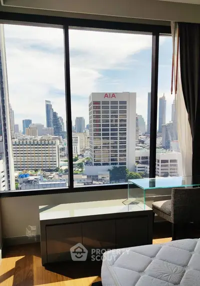 Stunning city view from modern high-rise apartment bedroom with large windows and sleek furnishings.