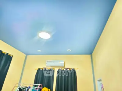 Spacious room with high ceiling and modern lighting, featuring air conditioning and dark curtains.