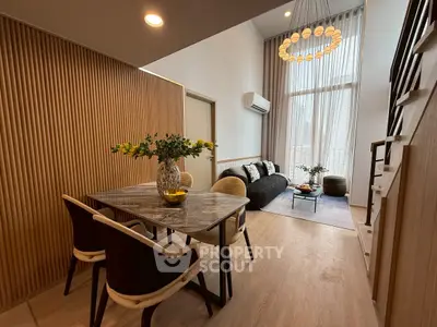 Modern living room with high ceilings and elegant dining area in a stylish apartment.