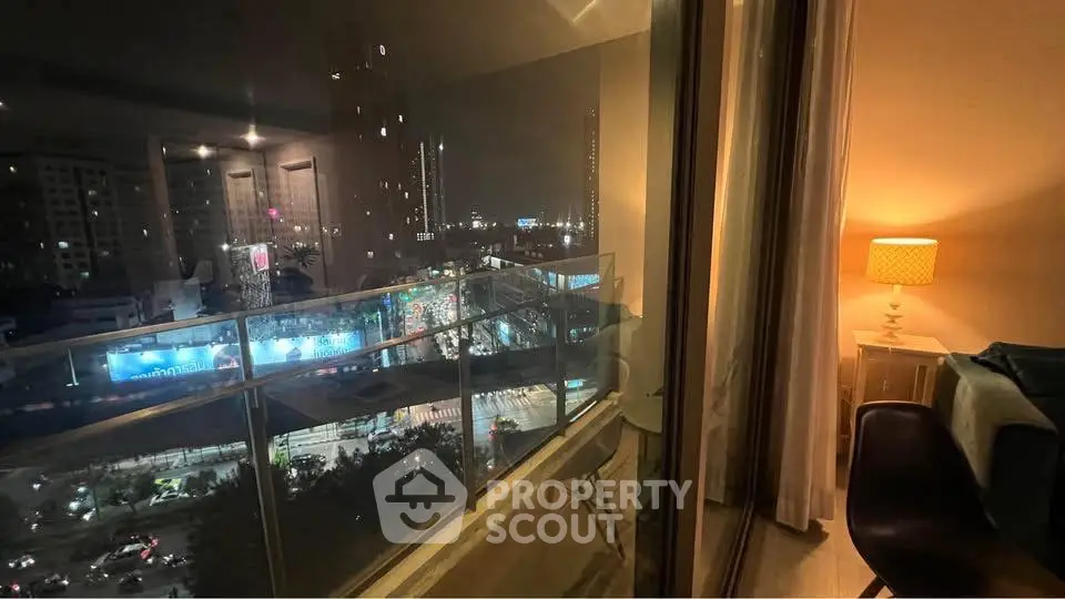 Stunning city view from modern apartment balcony at night, featuring cozy interior lighting.