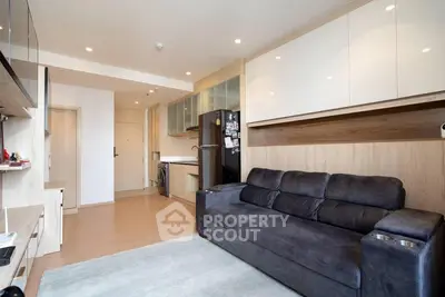 Modern living room with sleek design and open kitchen layout, featuring a cozy sofa and stylish cabinetry.