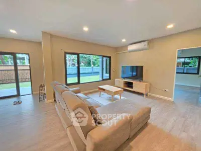 Spacious living room with modern furniture and large windows offering garden views.