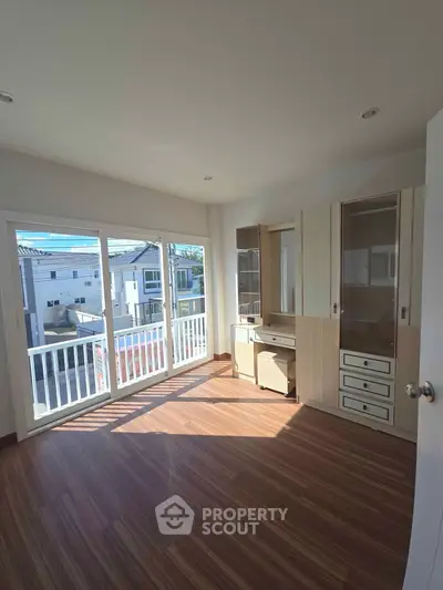 Bright bedroom with built-in storage and large windows overlooking a residential area.