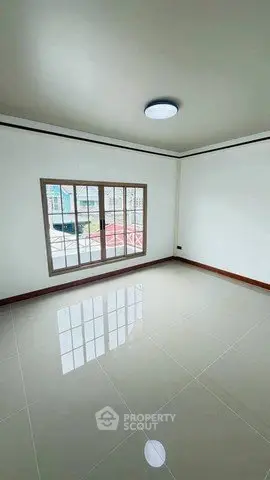 Spacious empty room with large window and glossy tiled floor, perfect for customization.