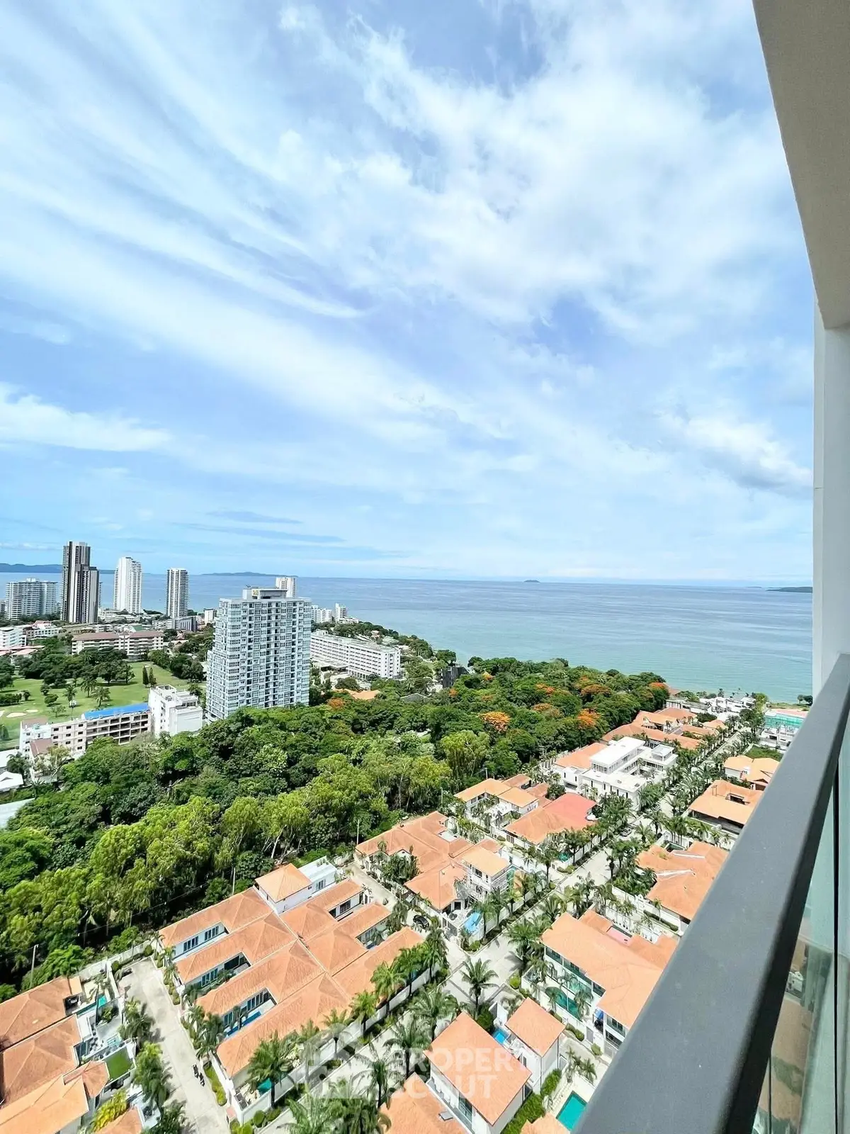 Stunning ocean view from high-rise balcony overlooking lush greenery and cityscape.