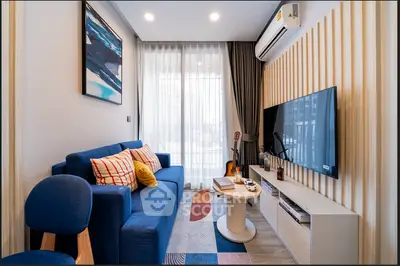 Modern living room with stylish decor, blue sofa, wall-mounted TV, and large window with curtains.