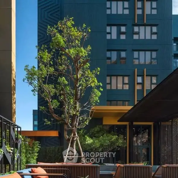Modern apartment building with lush greenery and stylish outdoor seating area.
