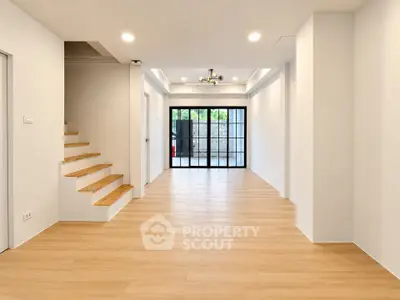 Spacious modern living room with wooden flooring and large glass doors.
