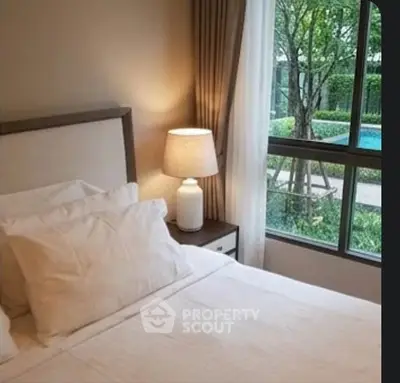 Cozy bedroom with pool view, featuring elegant decor and natural light through large window.