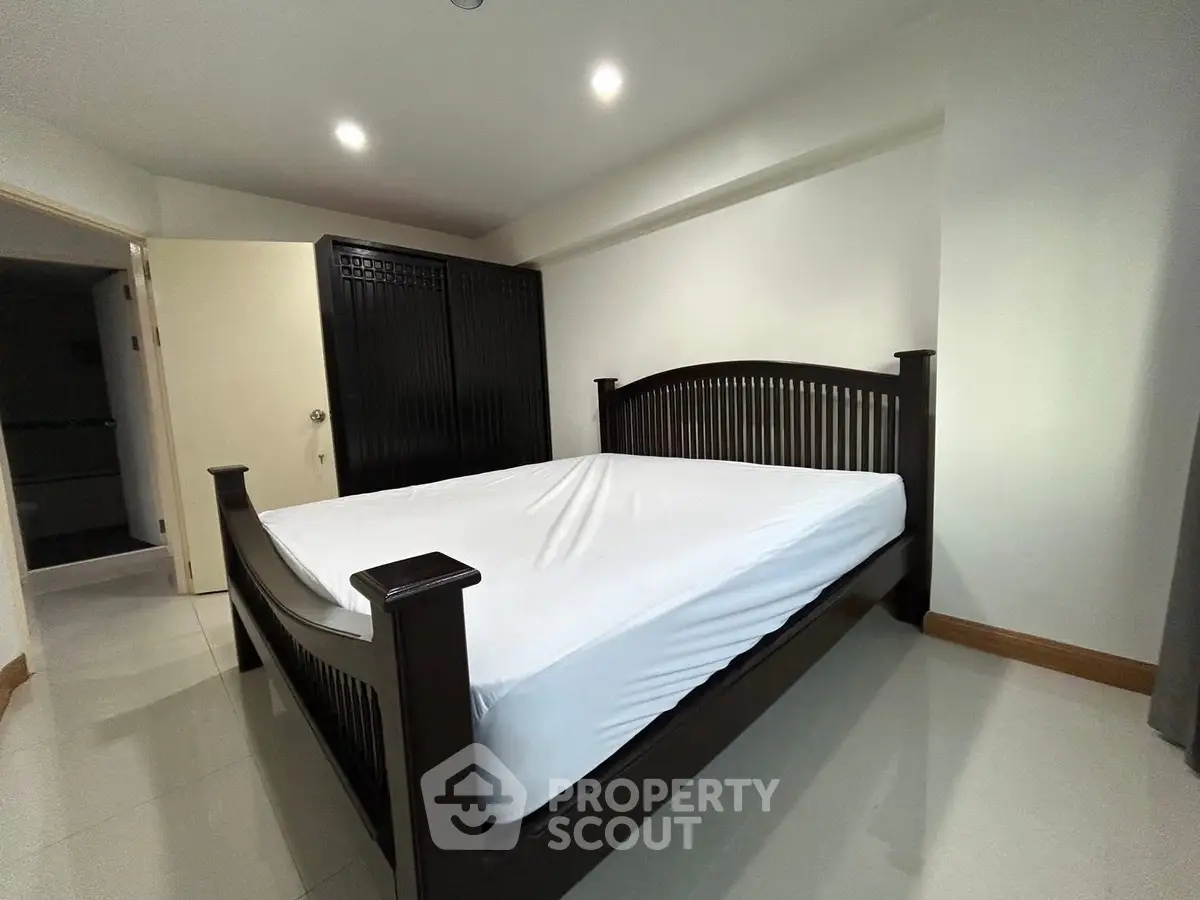 Spacious bedroom with elegant dark wood bed and wardrobe