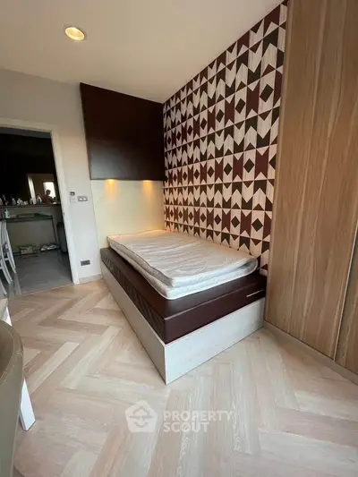 Stylish bedroom with geometric accent wall and cozy bed in modern apartment.