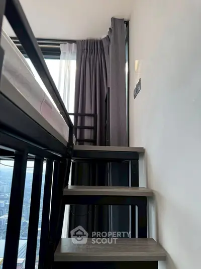 Modern loft bedroom with city view and sleek staircase design.