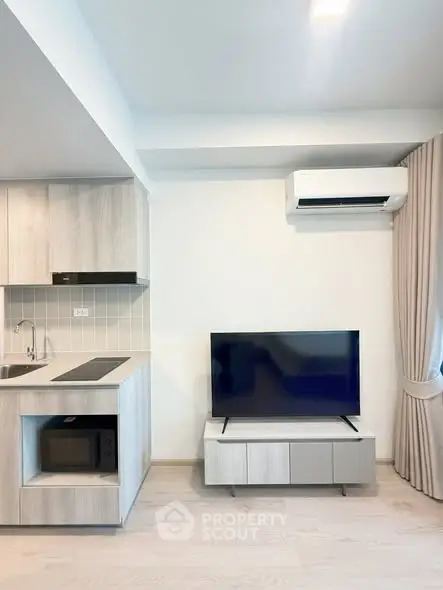 Modern living room with sleek kitchen, TV, and air conditioning in a stylish apartment.