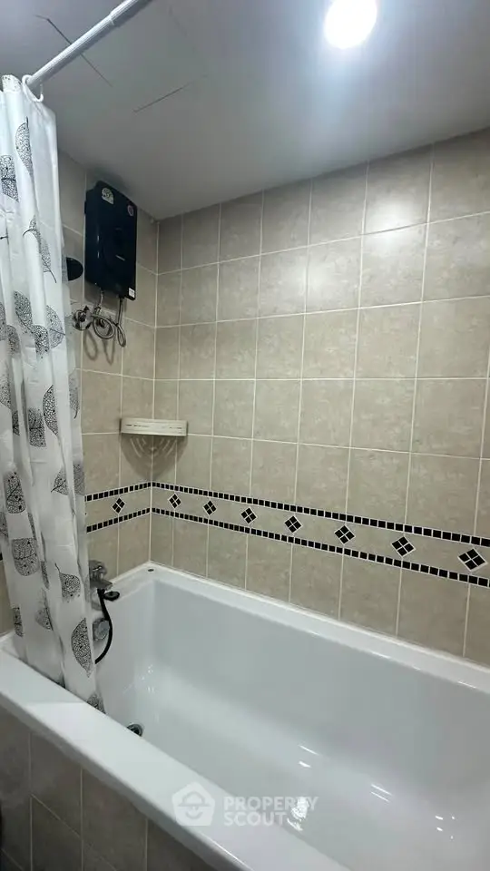 Modern bathroom with tiled walls and bathtub, featuring a shower curtain and water heater.