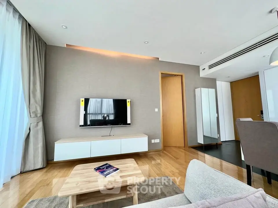 Modern living room with sleek design, wooden flooring, and natural light from large windows.