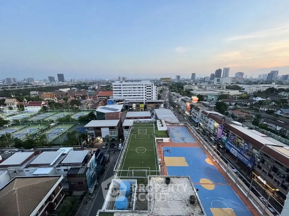 Stunning cityscape view from high-rise building overlooking sports courts and urban skyline.