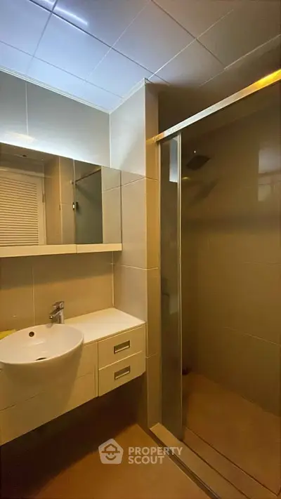Modern bathroom with sleek fixtures and glass shower enclosure in a contemporary home.