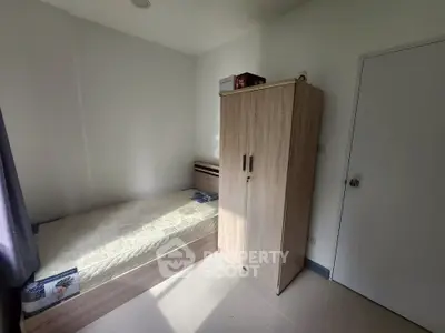 Cozy bedroom with natural light, featuring a single bed and wooden wardrobe, perfect for minimalist living.