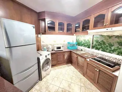Charming kitchen with modern appliances and wooden cabinetry, featuring a washing machine and spacious fridge.