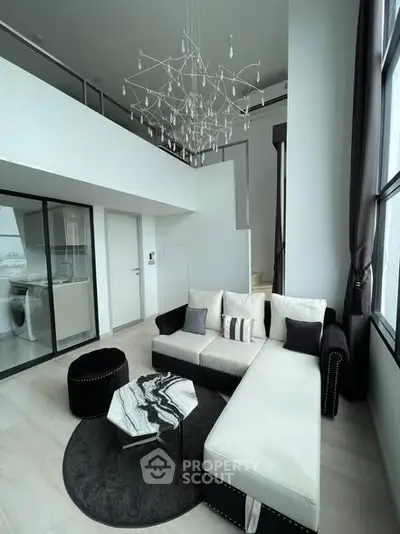 Luxurious modern living room with high ceilings and elegant chandelier in a stylish apartment.