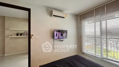 Modern bedroom with wall-mounted TV and large window with blinds