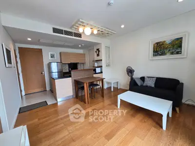 Modern living room with open kitchen, wooden flooring, and stylish decor in a cozy apartment.