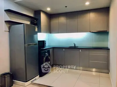 Modern kitchen with sleek cabinets, fridge, and washing machine in compact layout.