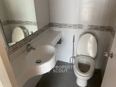 Modern bathroom with sleek white fixtures and large mirror in a contemporary home.
