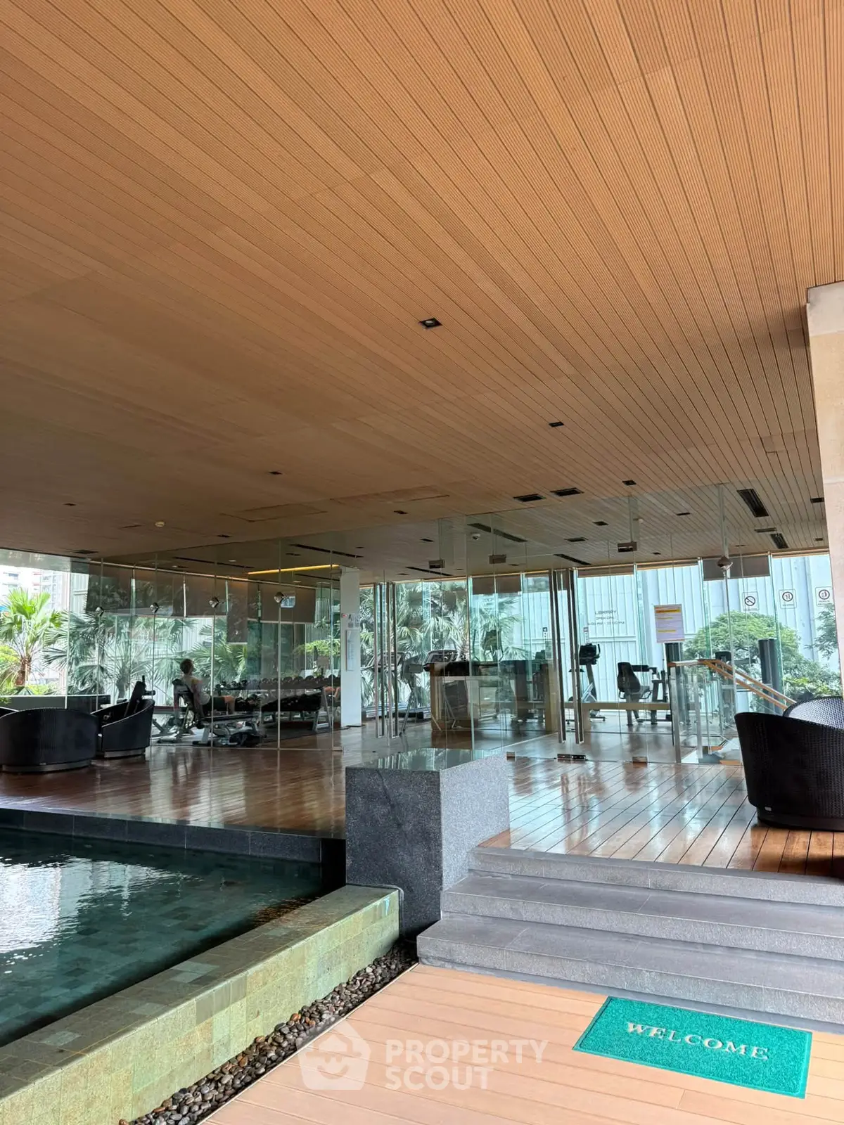 Luxurious gym with glass walls and pool in modern residential building