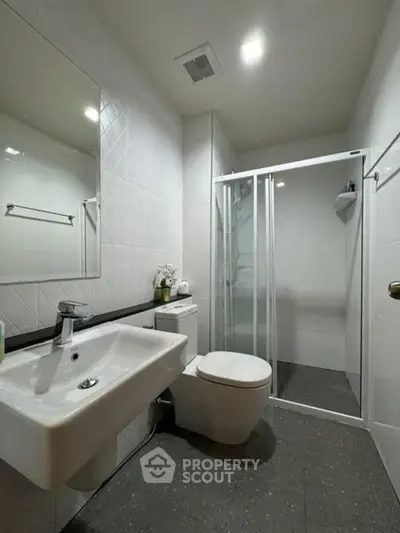 Modern bathroom with sleek fixtures and glass shower enclosure.