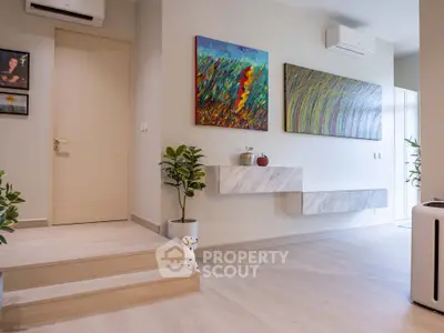 Modern living room with stylish decor and air conditioning, featuring vibrant artwork and sleek flooring.