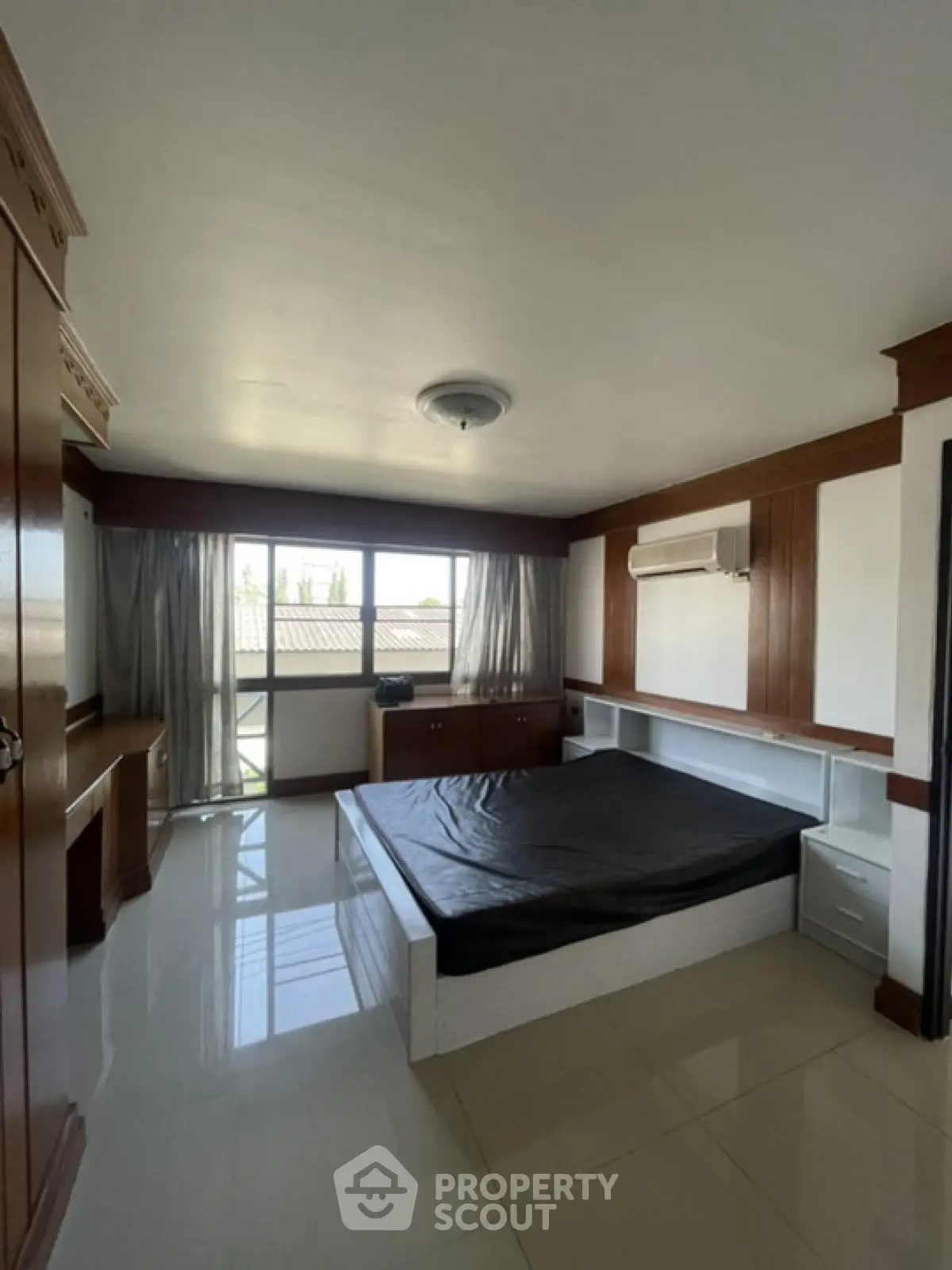 Spacious bedroom with large window and modern furnishings