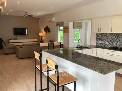 Spacious open-plan living room and kitchen with modern decor and ample natural light.