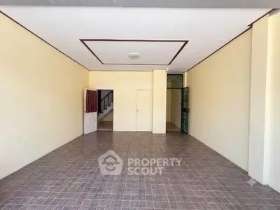 Spacious empty room with tiled flooring and ceiling light, ideal for customization.