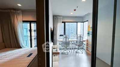 Modern apartment with bedroom and study area featuring large windows and city view.