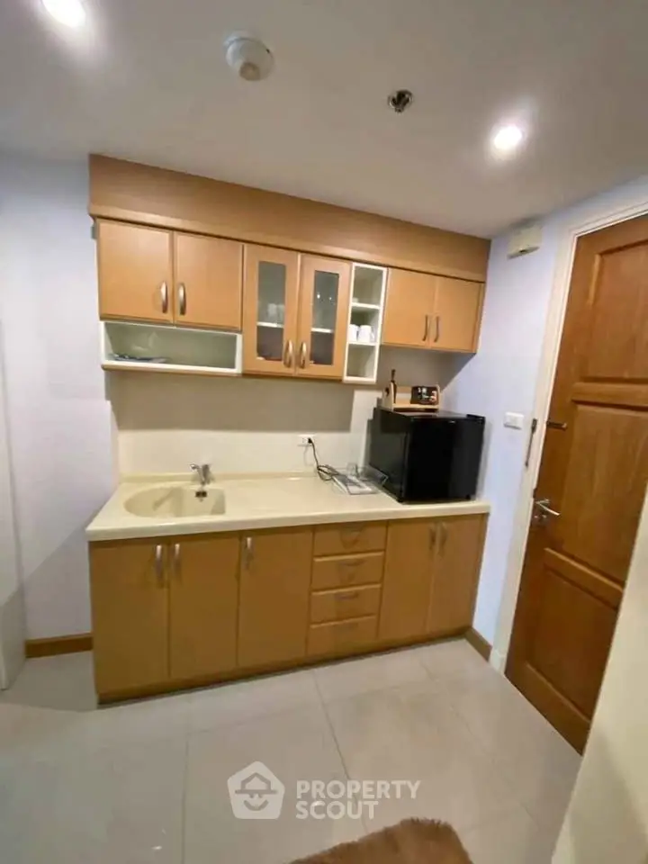Compact kitchen with wooden cabinets and modern appliances in cozy apartment
