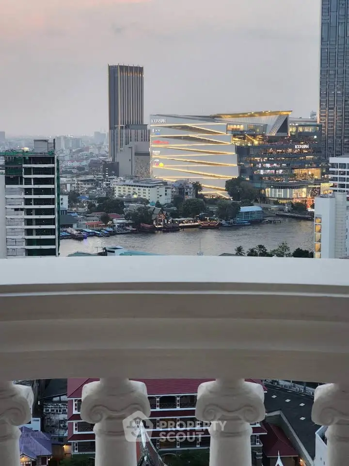 Stunning cityscape view from a balcony overlooking a river and modern buildings at dusk.