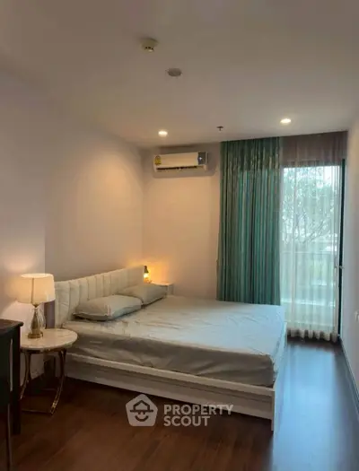 Spacious bedroom with modern decor and large window offering natural light.
